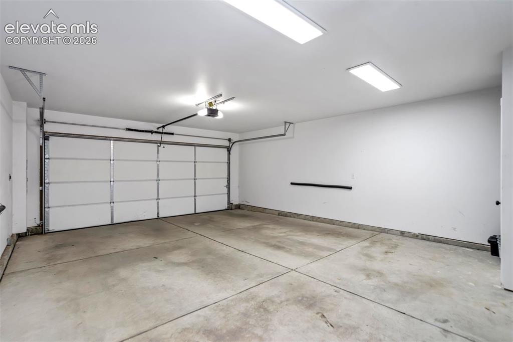Image 42 of 50: Spacious garage featuring a sectional overhead door, automatic opener, conc