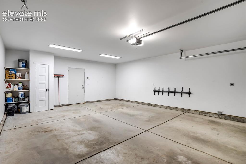 Image 43 of 50: Spacious garage featuring a concrete floor, bright overhead lighting, and a