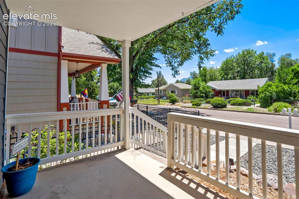 Image 5 of 50: Covered porch with white railings and concrete flooring