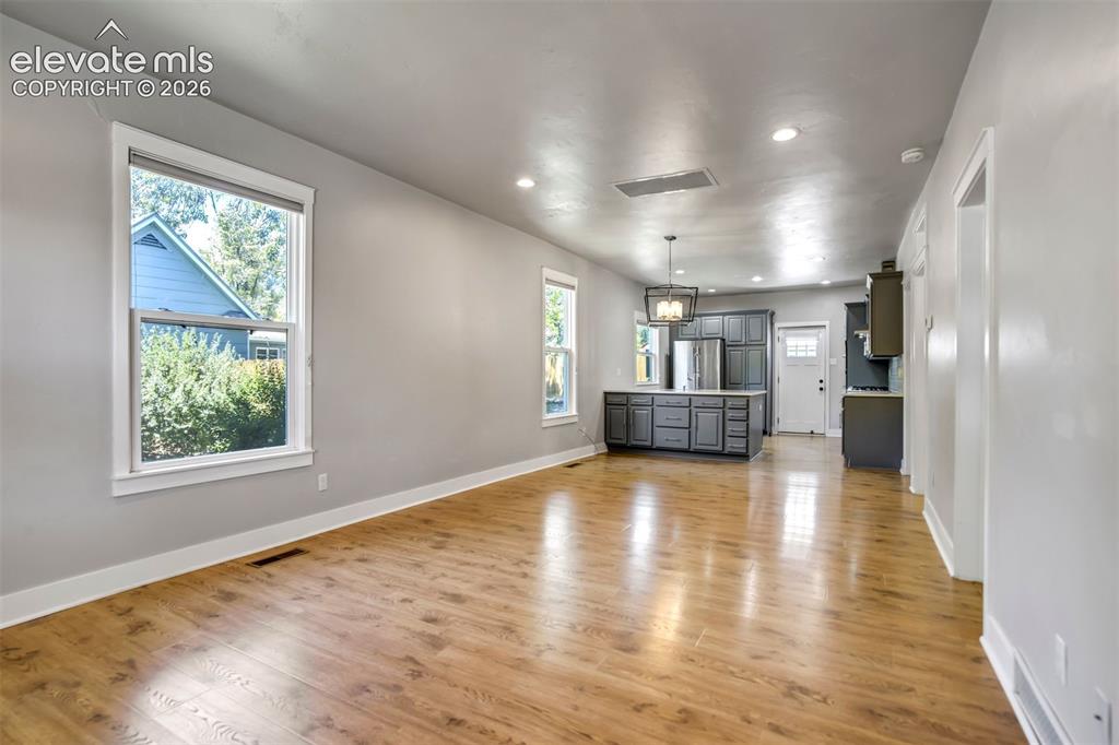 Image 7 of 50: Open-concept living space featuring wood-finish flooring, recessed lighting