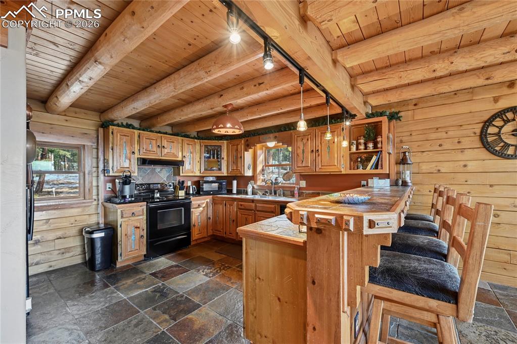 Image 14 of 43: Stone tile floors and more natural wood adorns the kitchen from floor to ce