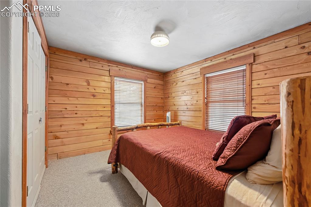 Image 18 of 43: Bedroom #2 of 5 has natural wood walls and carpet to keep your feet warm in