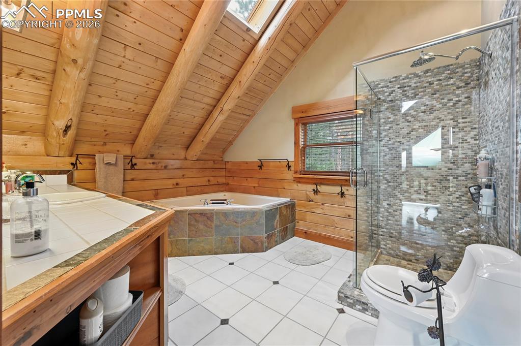Image 25 of 43: The master bathroom has gorgeous finishes in the stone mosaic shower, slate