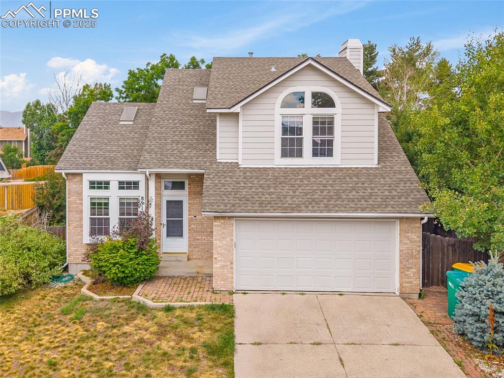 Caption: two-story home with a two car garage and covered front entrance. (photo has been edited to remove a 