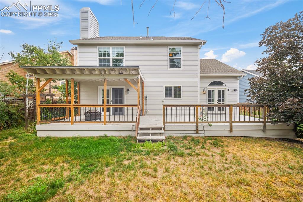 Image 3 of 50: back of the home, covered deck, and a large backyard