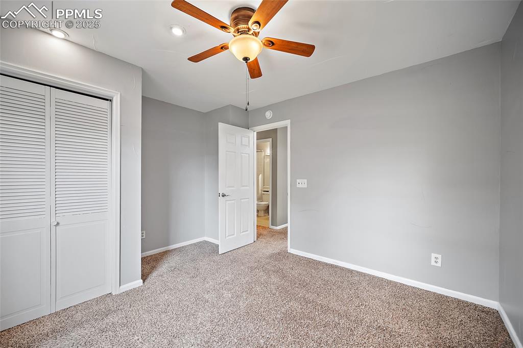 Image 30 of 50: primary bedroom with an ensuite, ceiling fan, and double closet