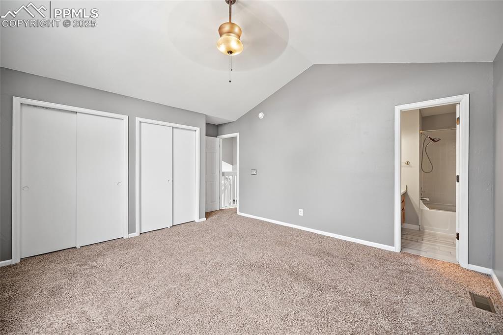 Image 31 of 50: primary bedroom with an ensuite, ceiling fan, and double closet