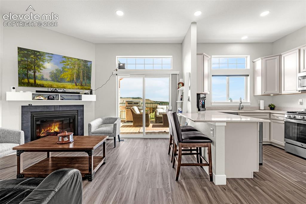 Image 18 of 33: LVP flooring, living room with gas fireplace, kitchen, and a balcony
