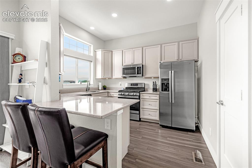 Image 19 of 33: LVP flooring, living room with gas fireplace, kitchen, and a balcony