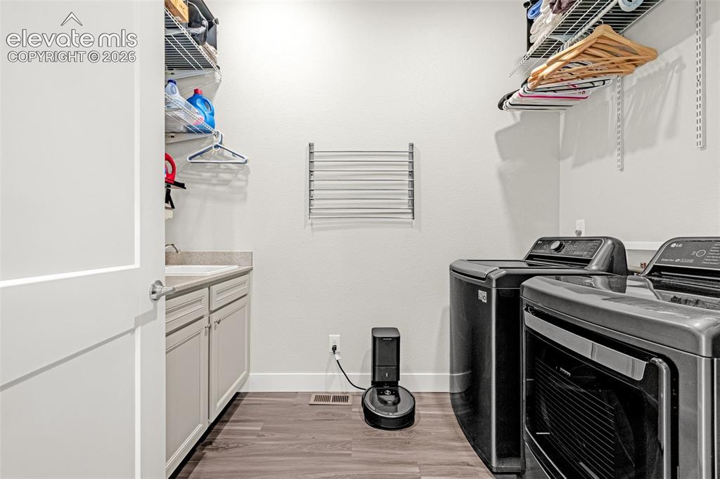 Image 28 of 33: Main level laundry room, sink, many built in shelves and clothing racks.