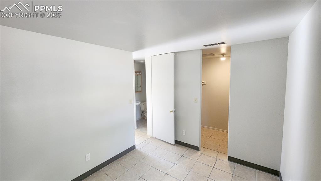 Image 12 of 15: Unfurnished bedroom featuring light tile patterned floors, baseboards, and
