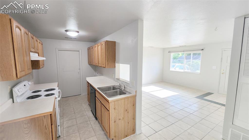 Image 5 of 15: Kitchen with white electric range oven, a sink, under cabinet range hood, b
