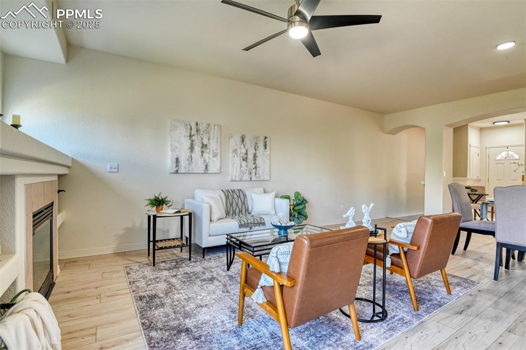 Image 11 of 46: Living room featuring a tiled fireplace, light wood-style flooring, arched