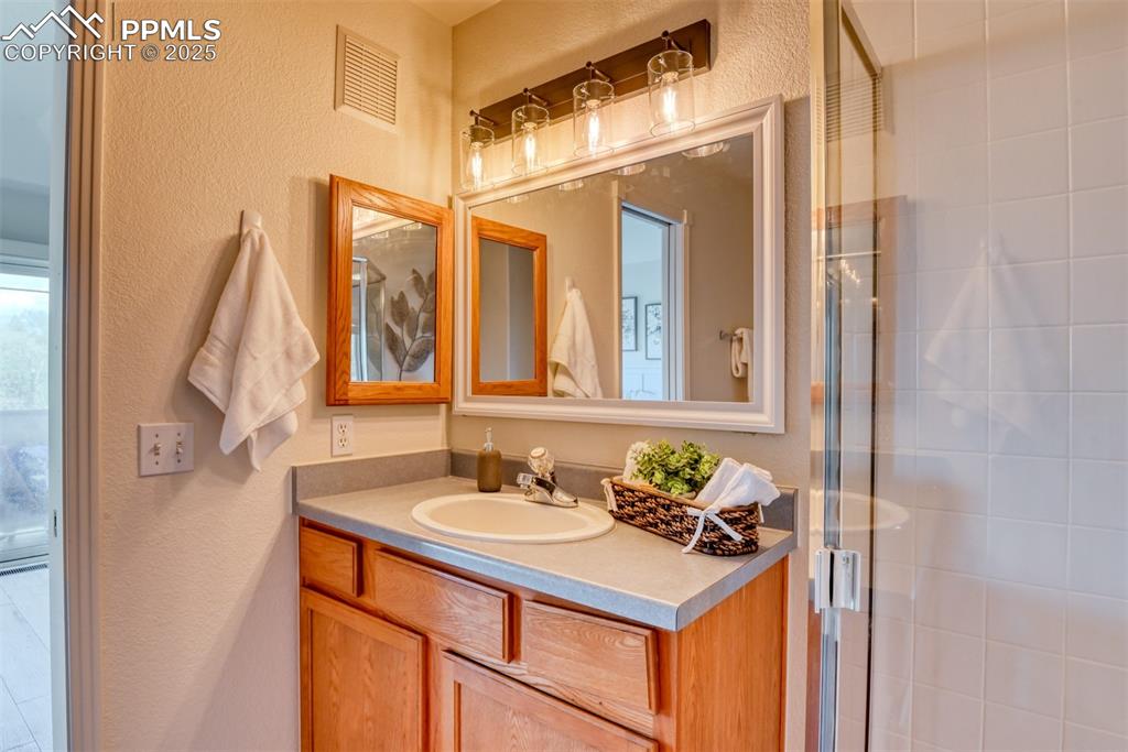 Image 20 of 46: Bathroom featuring a textured wall, vanity, and a shower stall