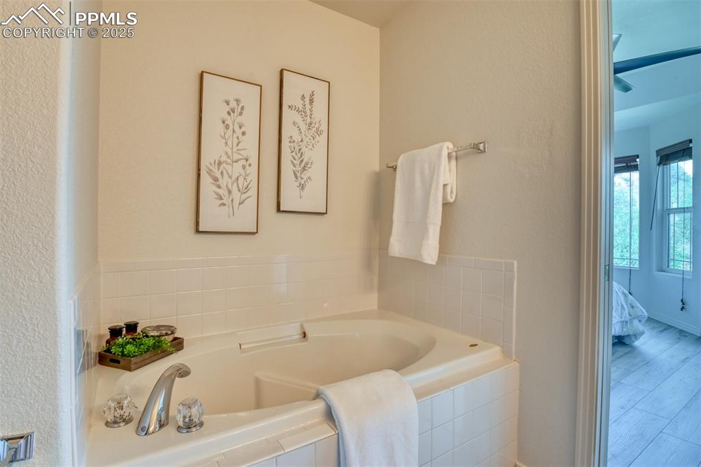 Image 21 of 46: Bathroom featuring ensuite bathroom, a garden tub, a textured wall, and woo