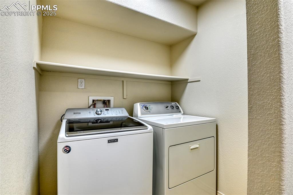 Image 44 of 46: Laundry area featuring a textured wall and washing machine and clothes drye