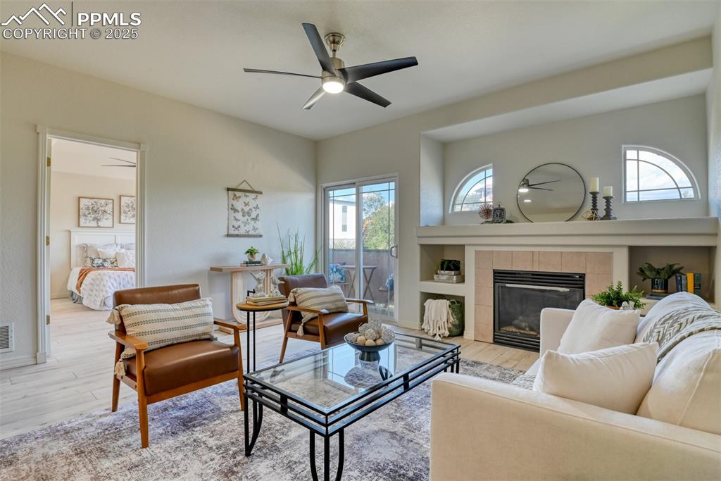 Image 5 of 46: Living room featuring a ceiling fan, wood finished floors, and a fireplace