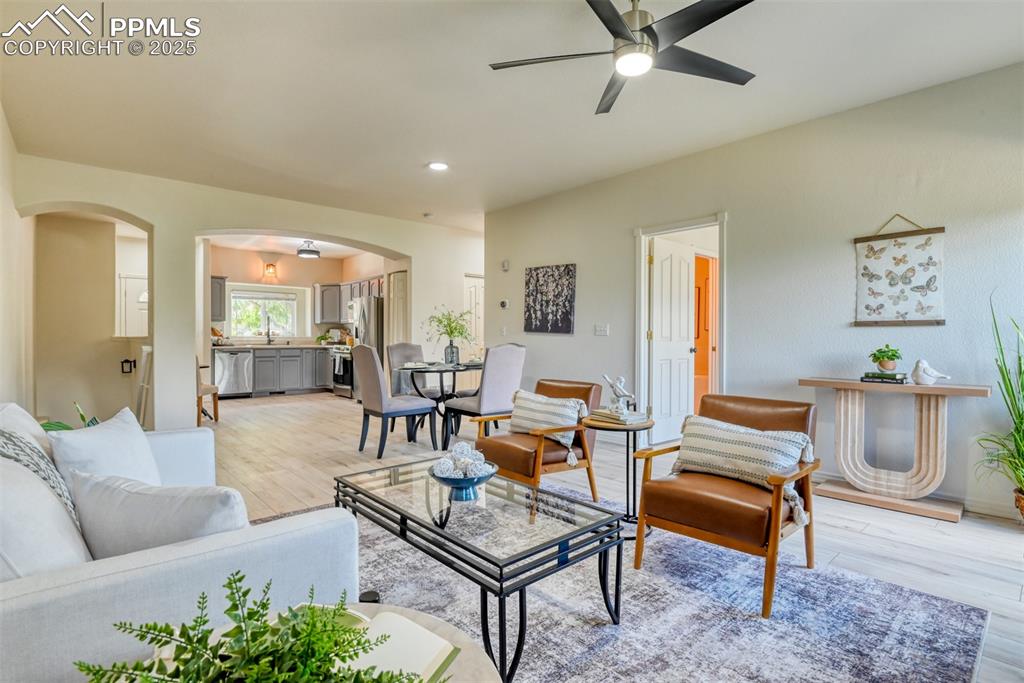 Image 7 of 46: Living room featuring light wood-style flooring, a ceiling fan, arched walk