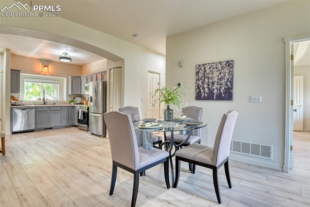 Image 9 of 46: Dining area featuring light wood finished floors and arched walkways