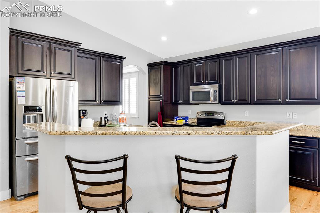 Image 10 of 37: Kitchen featuring light wood-style flooring, lofted ceiling, stainless stee