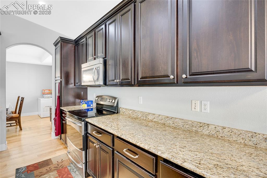 Image 11 of 37: Kitchen with arched walkways, stainless steel appliances, light stone count