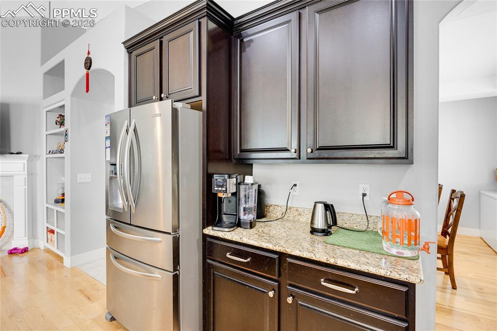 Image 12 of 37: Kitchen featuring dark wood finish cabinetry, stainless steel fridge with i