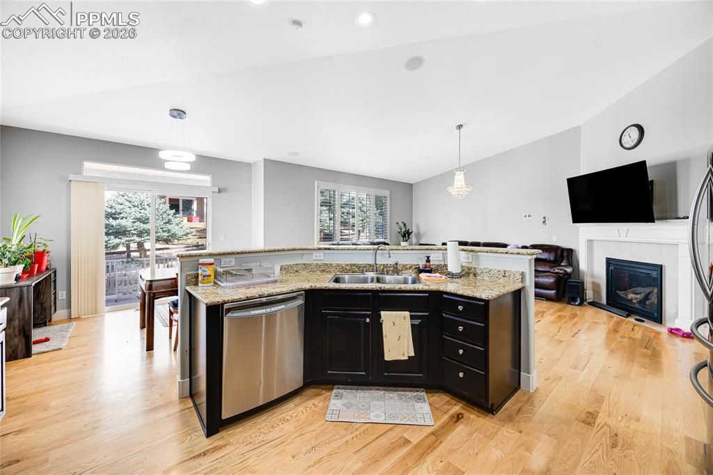 Image 13 of 37: Kitchen with dark cabinets, open floor plan, a kitchen island with sink, a