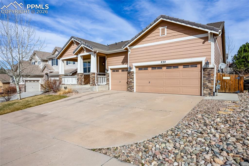 Image 2 of 37: Craftsman house with stone siding, an attached garage, driveway, a tile roo