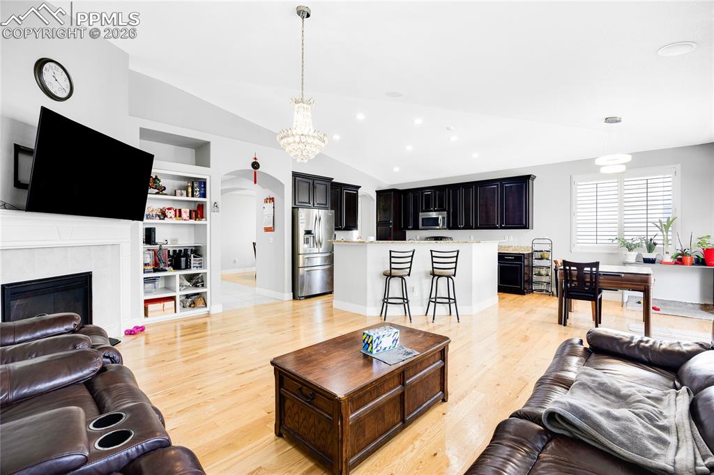 Image 7 of 37: Living room with arched walkways, built in shelves, vaulted ceiling, a tile