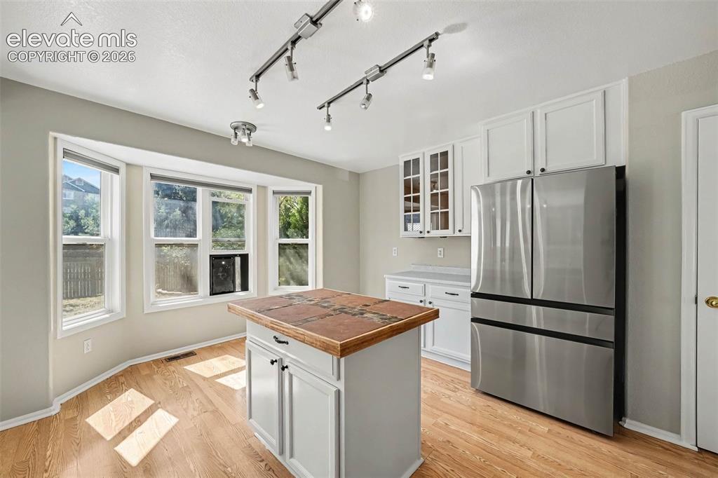 Image 10 of 31: Kitchen featuring wood-finish flooring, white cabinetry, stainless steel ap
