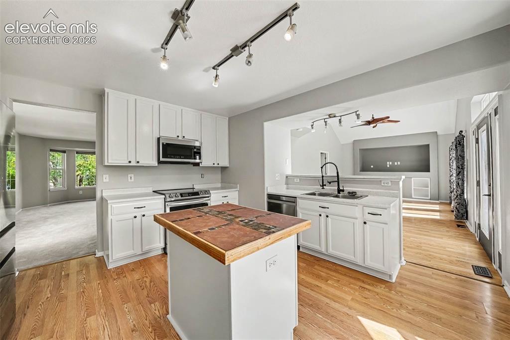 Image 11 of 31: Kitchen featuring white cabinetry, stainless steel appliances, a center isl