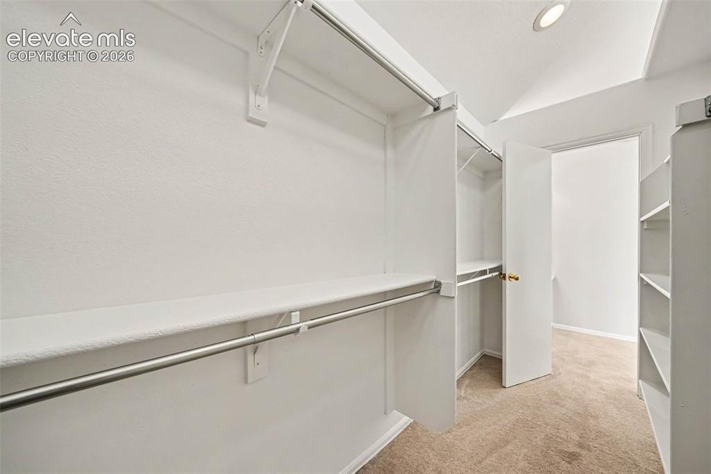 Image 19 of 31: Spacious walk-in closet featuring dual clothing rods, abundant shelving, so