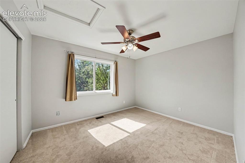 Image 20 of 31: Carpeted room featuring a ceiling fan with light fixture, a window, a skyli
