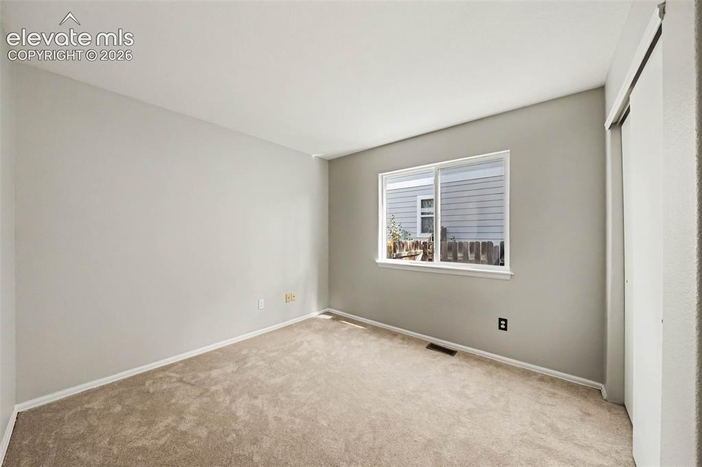 Image 21 of 31: Carpeted flooring, neutral wall color, white trim, sliding closet doors, an