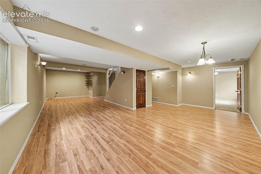 Image 25 of 31: Expansive room featuring wood-finish flooring, recessed lighting, wall scon