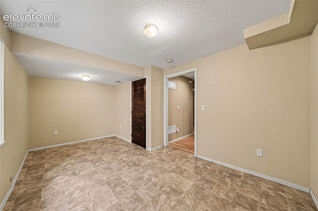 Image 27 of 31: Tile-patterned flooring, recessed lighting, and a wood-finish door