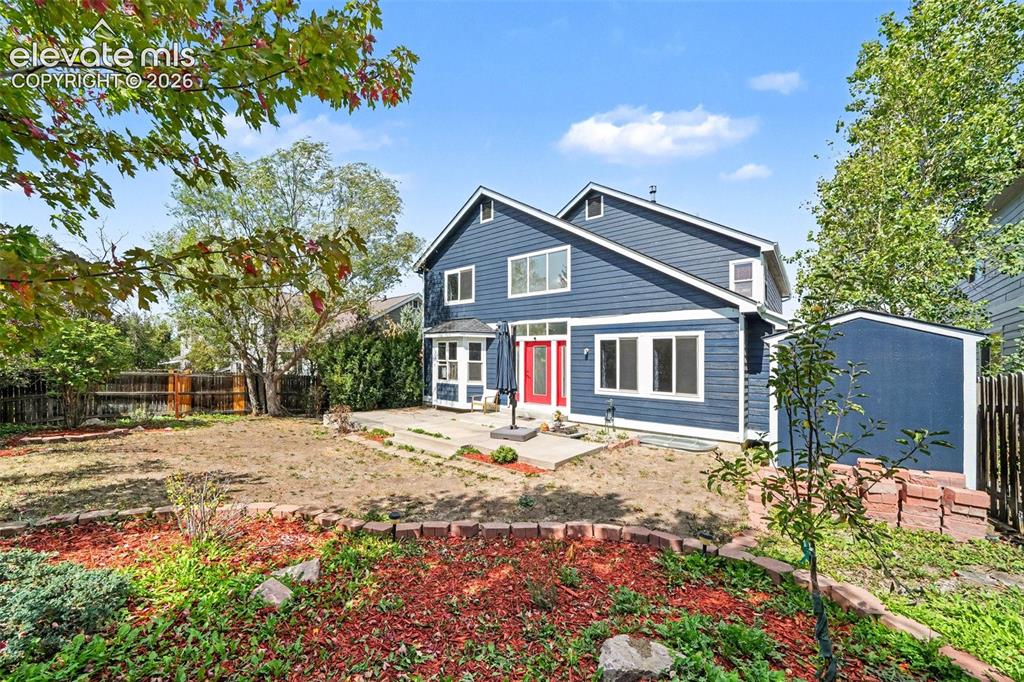 Image 29 of 31: Expansive rear yard featuring a large patio, built-in garden beds, and a de