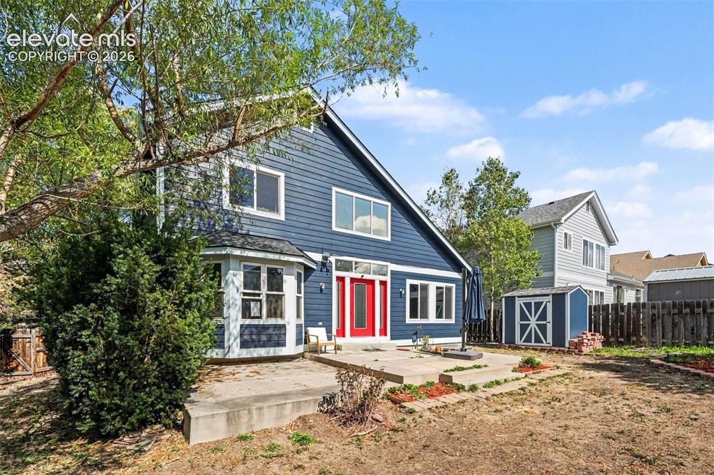 Image 31 of 31: Exterior featuring blue horizontal siding, white trim, red entry door, bay 