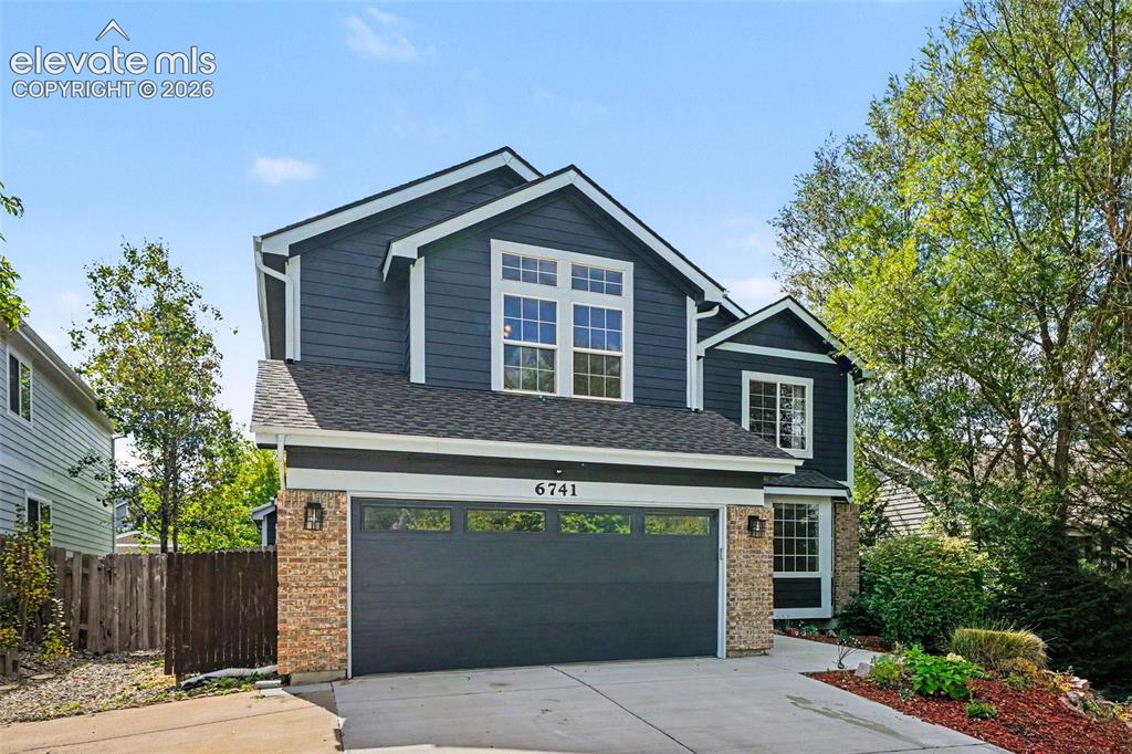 Image 4 of 31: Two-story residence featuring dark siding and brick accents