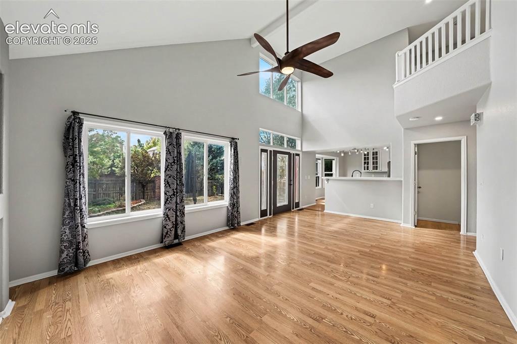 Image 7 of 31: Vaulted ceilings, wood-finish flooring, and multiple windows with transoms