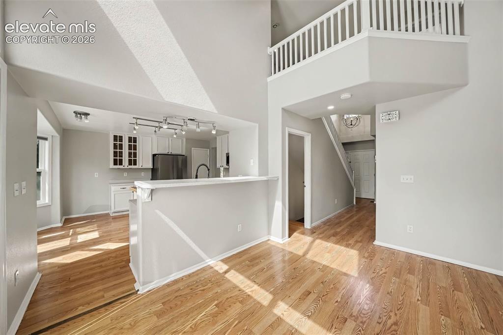 Image 9 of 31: Vaulted ceiling, wood-finish flooring, white kitchen cabinetry, stainless s
