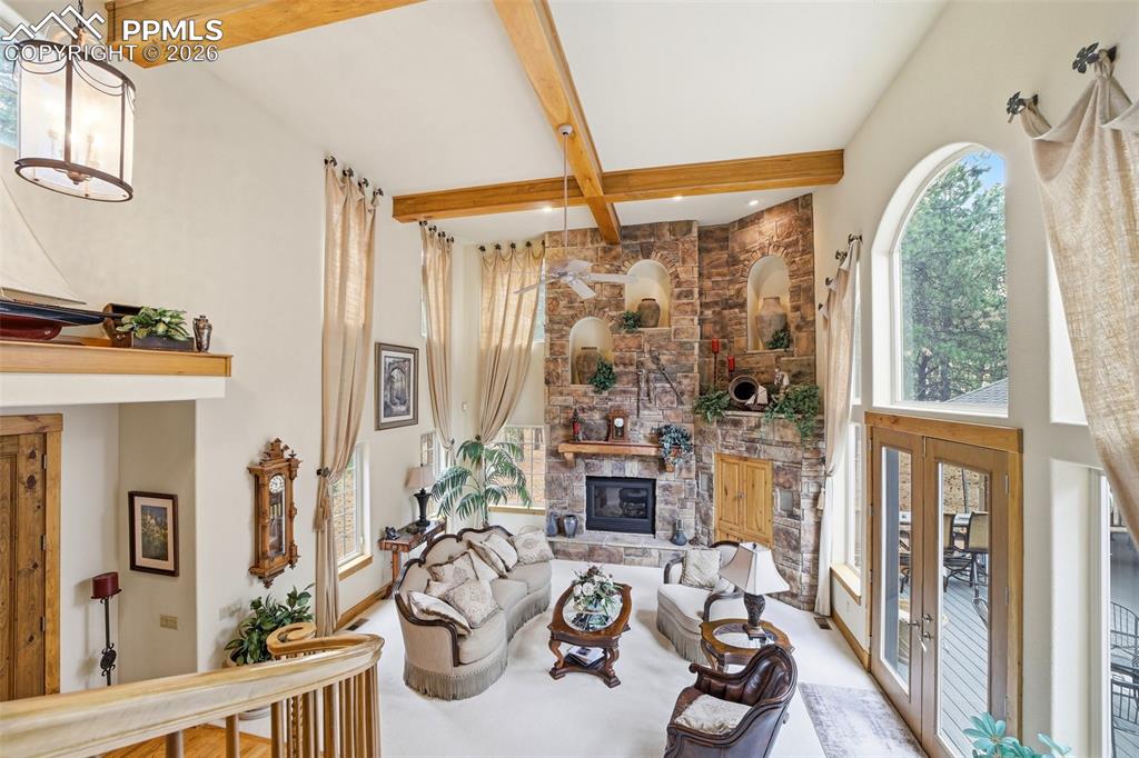 Image 17 of 50: 2 Story high Living room with a hearth stack and stoned fireplace surround 