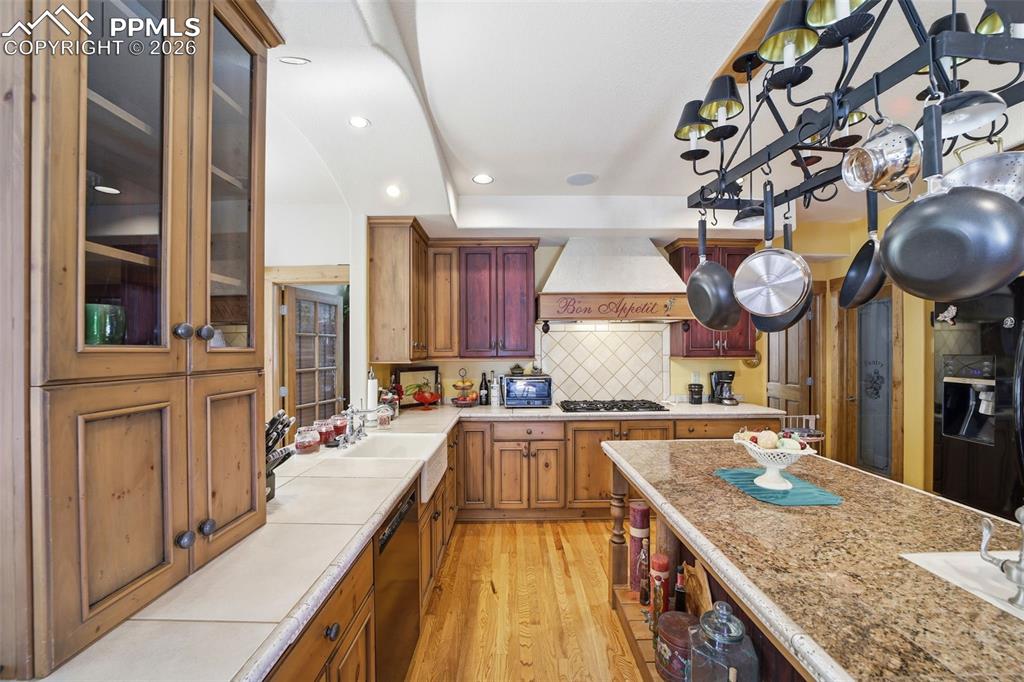 Image 22 of 50: Kitchen featuring glass insert cabinets, tasteful backsplash, light wood fi