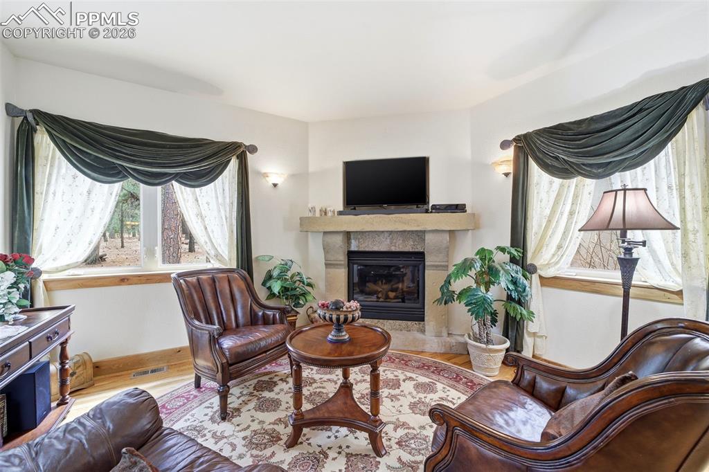 Image 27 of 50: Conversation Den with a tile fireplace and wood finished floors