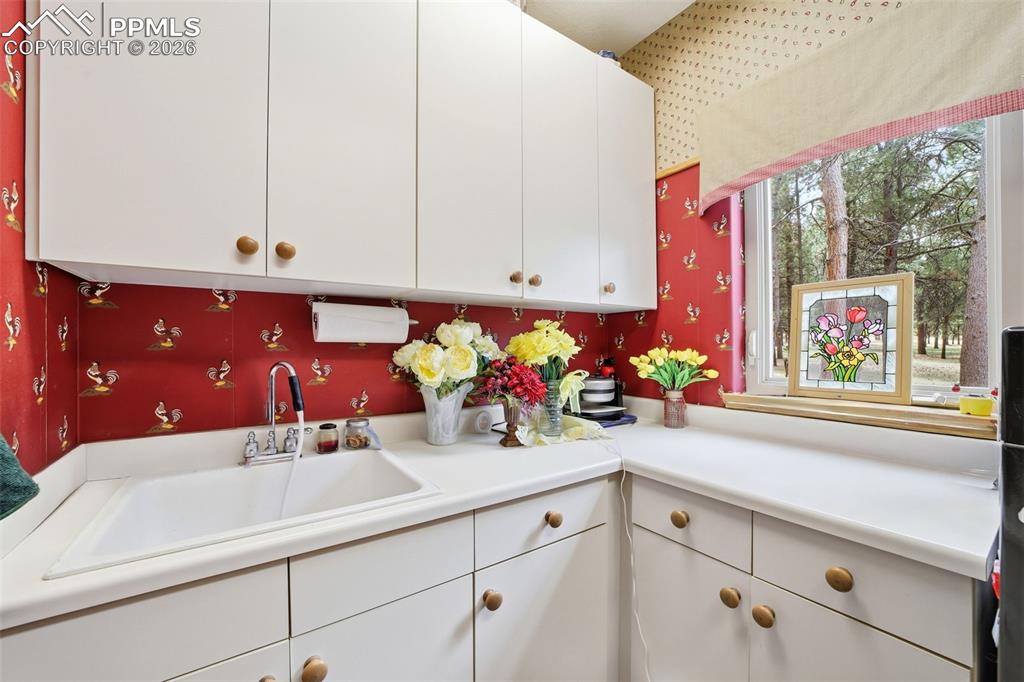 Image 31 of 50: Laundry room with sink and window and white cabinets 