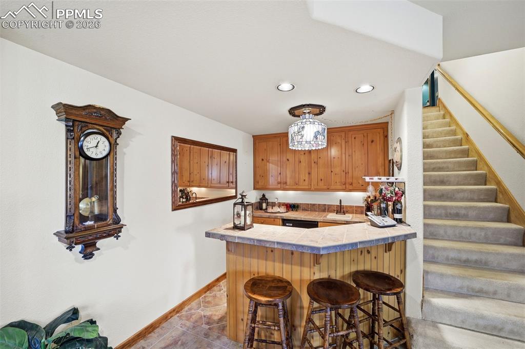 Image 32 of 50: Basement Wet Bar with tile countertops, a peninsula, a breakfast bar area, 