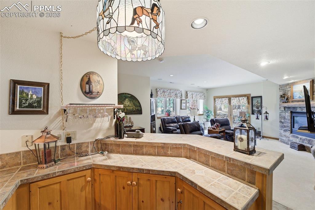 Image 33 of 50: Wet Bar in basement featuring open floor plan, a peninsula, a stone firepla