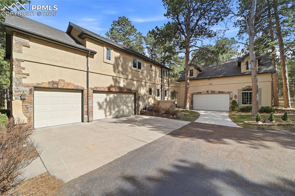 Image 4 of 50: 6 car oversized garage entrances with concrete pad and asphalt driveway
