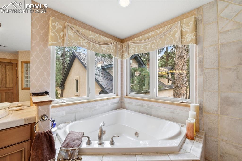 Image 44 of 50: Full bathroom with vanity and a whirlpool tub