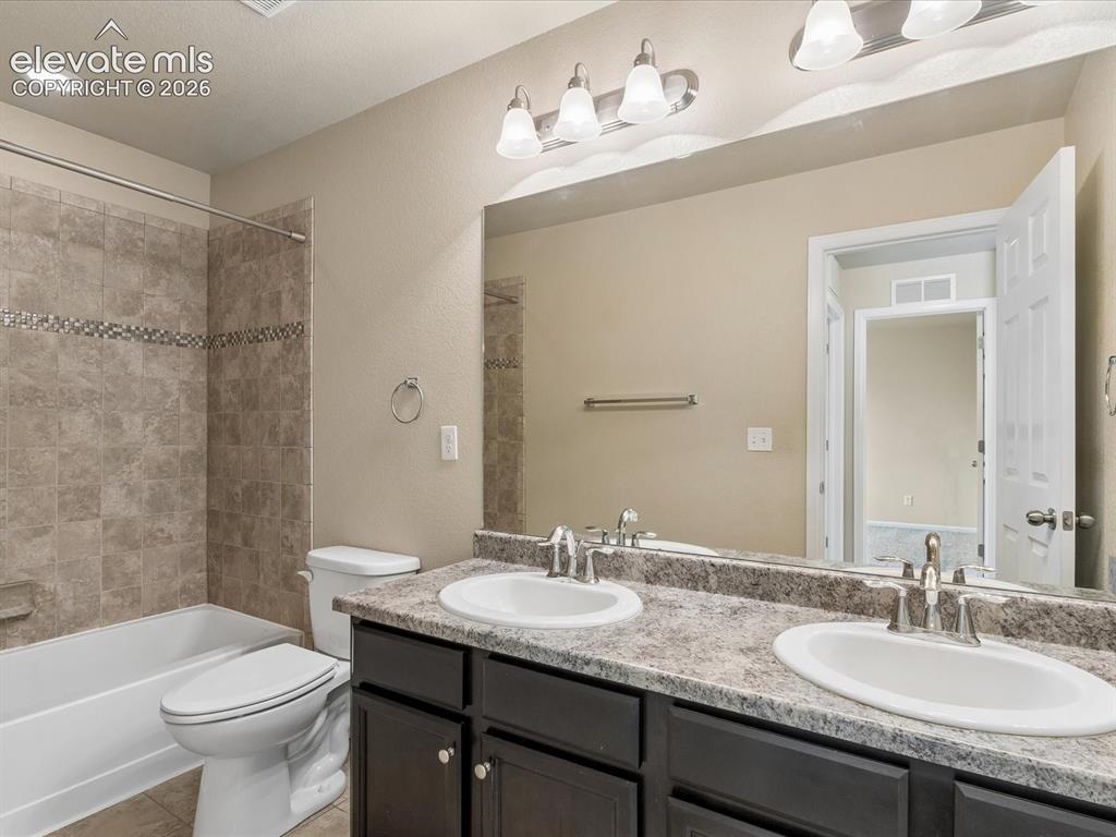Image 12 of 23: Bathroom featuring a double vanity with an integrated sink, patterned count
